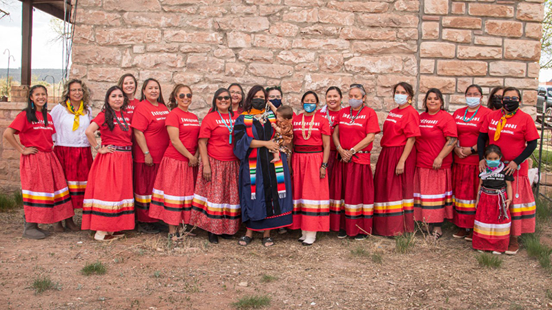 Dr. Cristina Carpenter and some of her mentors and support system at her graduation reception, May 2021. From left to right, Mariah (daughter of Cheryl), Lynn, Joanna, Mia, Delilah, Cheryl, Adriann (Begay), Cristina and Anika, Nina, Tiffin, Marla, Velma, Thomacita, Dacia, Germaine (daughter of Leah), Bernie, and Leah and Rylee. Cristina would also like to acknowledge those who aren't shown in this photo.